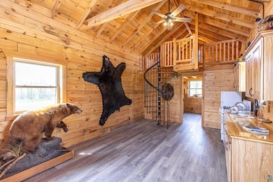 Interior space with wooden walls, wooden ceiling, wood finished floors, ceiling fan, and stairway