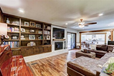 Living area with fireplace, built in shelving, can lighting and ceiling fan.