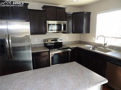 Kitchen featuring stainless steel appliances, light countertops, and dark brown cabinetry