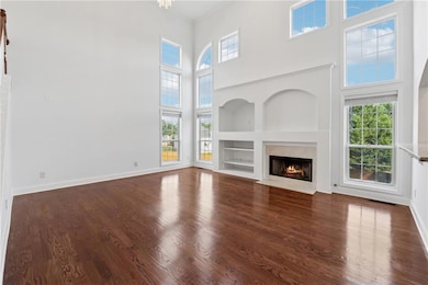Unfurnished living room with a high ceiling, dark wood finished floors, healthy amount of natural light, and a premium fireplace