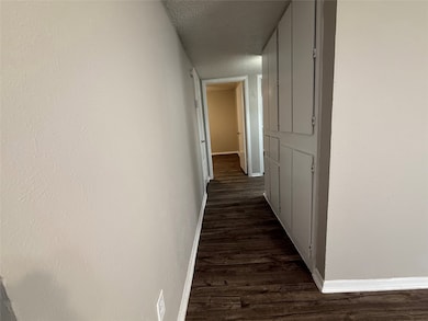 Corridor featuring a textured ceiling and dark wood-type flooring