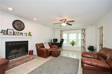 ***ACTUAL PICTURE***Living room featuring light tile patterned flooring, ornamental molding, a ceiling fan, a brick fireplace, and recessed lighting