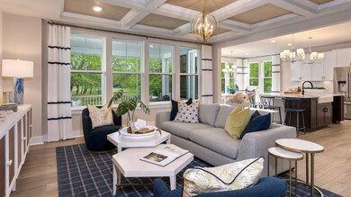 Open main floor with walls of windows & wood floors in a DRB Homes Barbados model home in The Estuary community.