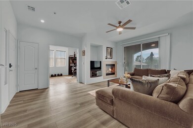 Living area with a fireplace, ceiling fan, and lig