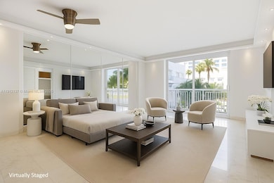 Sunlight fills the open space through floor-to-ceiling sliding doors, highlighting the gleaming floors and mirrored accent wall that enhances depth and natural light. The modern layout seamlessly connects to a private balcony with lush palm views, creating a serene indoor-outdoor flow. Clean lines, recessed lighting, and refined finishes make this residence the perfect blend of luxury and tranquility