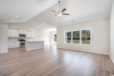 Unfurnished living room with a ceiling fan, a sink, a chandelier, light wood finished floors, and high vaulted ceiling