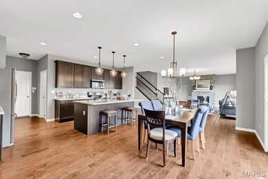 Dining room with light wood-type flooring, a stone fireplace, recessed lighting, a chandelier, and stairway
