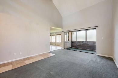 Living room has soaring ceilings and an oversized sliding glass door that opens up to a private balcony.