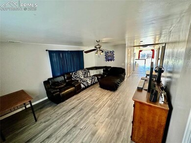 Living room with ceiling fan, baseboards, and wood