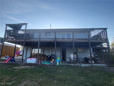 Back of property featuring a deck, a patio, and a lawn