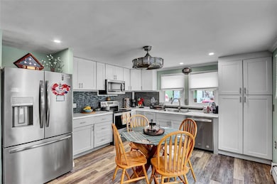 Kitchen with stainless steel appliances, light countertops, tasteful backsplash, recessed lighting, and light wood finished floors