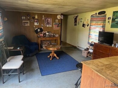 Living room featuring baseboard heating, concrete floors, and wood walls