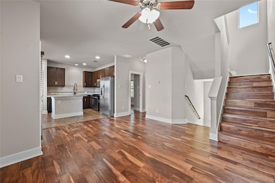 Unfurnished living room featuring dark wood finished floors, ceiling fan, recessed lighting, and stairway