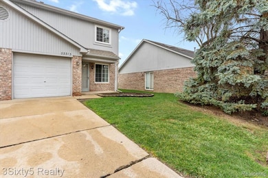 Traditional-style home featuring a front yard, driveway, brick siding, and covered porch