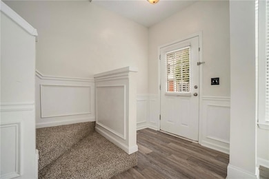 Foyer featuring a decorative wall, wood finished floors, and a wainscoted wall