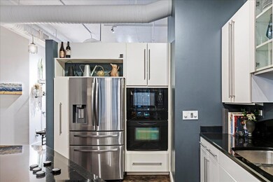 Kitchen with black appliances, white cabinetry, a
