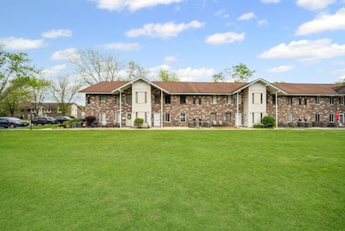 View of front of home with brick siding, a front lawn, and cooling unit