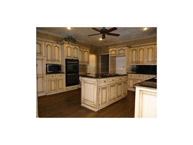 This Spacious Kitchen Features Plenty of Cabinetry, a Pantry, a Large Kitchen Island with Built In Cook Top, a Ceiling Fan, New Whirlpool Double Oven, Crown Molding & Faux Painted Walls.