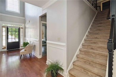 Entryway with wood finished floors, stairway, and crown molding