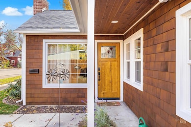 View of exterior entry with a chimney and roof with shingles