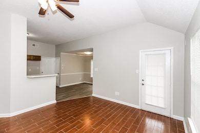 Spare room featuring dark wood-type flooring, a ceiling fan, and lofted ceiling