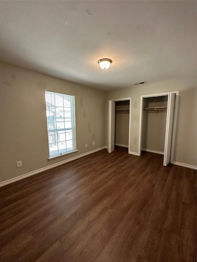 Unfurnished bedroom with baseboards, dark wood-st