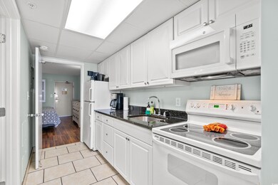 Kitchen with light wood-type flooring, white appli