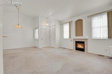 Living room with carpet, a fireplace, and vaulted ceiling