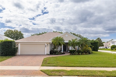 View of front facade with a front yard, stucco siding, decorative driveway, and roof with shingles