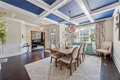 Dining room with a chandelier, wainscoting, coffered ceiling, beam ceiling, and wood finished floors