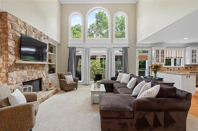 Living area featuring a stone fireplace, a high ceiling, and light colored carpet