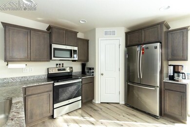 Kitchen featuring dark brown cabinets, light hardw
