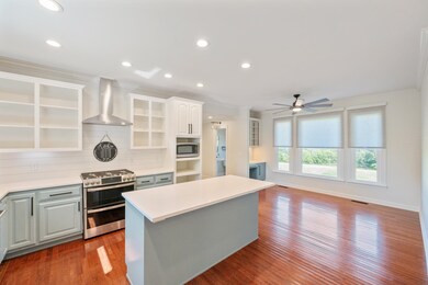 Kitchen with stainless steel appliances, wall chimney range hood, recessed lighting, light wood-style flooring, and crown molding