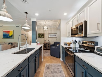 Kitchen featuring stainless steel appliances, open floor plan, light stone countertops, hanging light fixtures, and backsplash