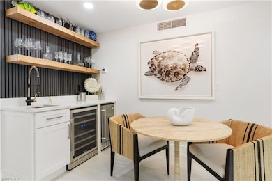 Bar with wine cooler, sink, and white cabinetry