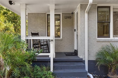 Entrance to property with brick siding and a porch
