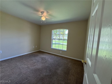 Unfurnished room featuring dark carpet and ceiling fan