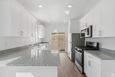 Kitchen with light stone countertops, appliances with stainless steel finishes, white cabinetry, and recessed lighting