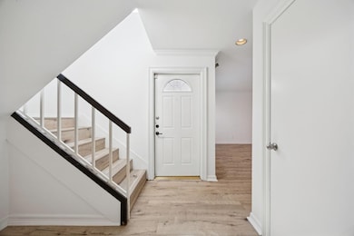 Foyer featuring recessed lighting, light wood-style flooring, stairs, and crown molding