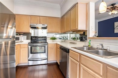 Kitchen with stainless steel appliances, under cabinet range hood, light brown cabinets, and ornamental molding