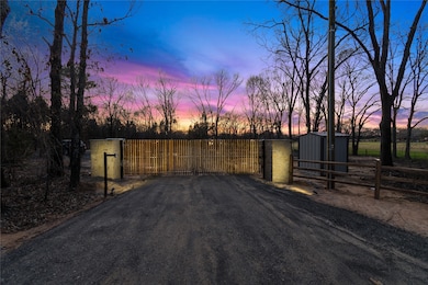View of asphalt driveway with a gate and a gated entry