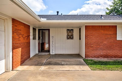 Property entrance featuring roof with shingles and brick siding