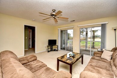 Living room with a ceiling fan, light colored carpet, and a textured ceiling