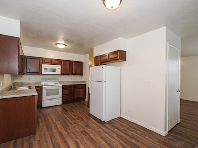 Kitchen with white appliances, light countertops, a textured ceiling, and dark wood-style floors