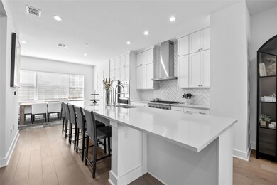 Kitchen with white cabinets, tasteful backsplash, light wood-style flooring, a spacious island, and a breakfast bar area