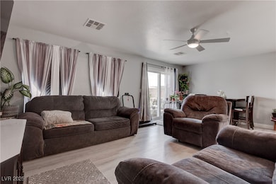 Living room featuring a ceiling fan and light wood