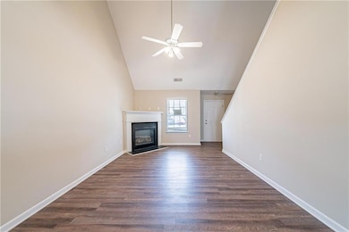 Unfurnished living room featuring baseboards, a ceiling fan, a glass covered fireplace, dark wood-style flooring, and high vaulted ceiling