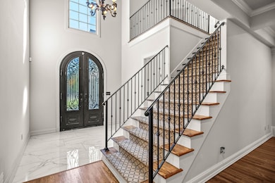 Entryway with french doors, arched walkways, marble finish floors, a chandelier, and stairway