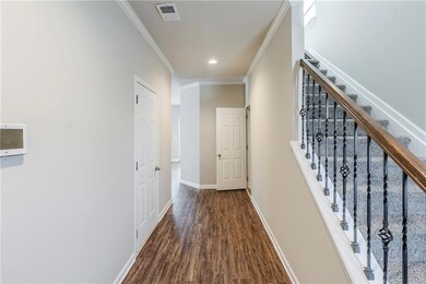 Corridor featuring stairway, wood finished floors, baseboards, visible vents, and ornamental molding