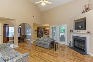 Open living room with high ceilings and laminate hardwoods. Cozy up to gas fireplace. The double doors that are letting natural light shine in, lead to the back patio.